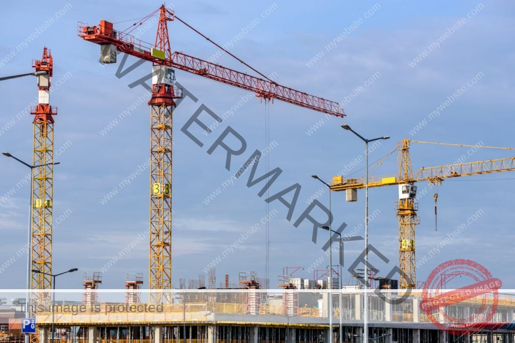 Three Yellow and Red Tower Cranes Under Clear Blue Sky